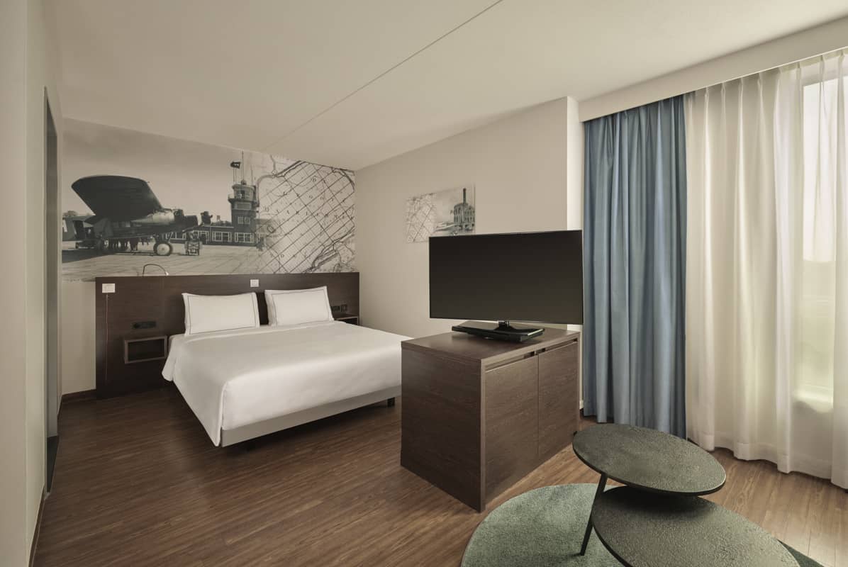 Grote kamer met een queen-size bed, een tv-meubel van donker hout, twee zwarte salontafels