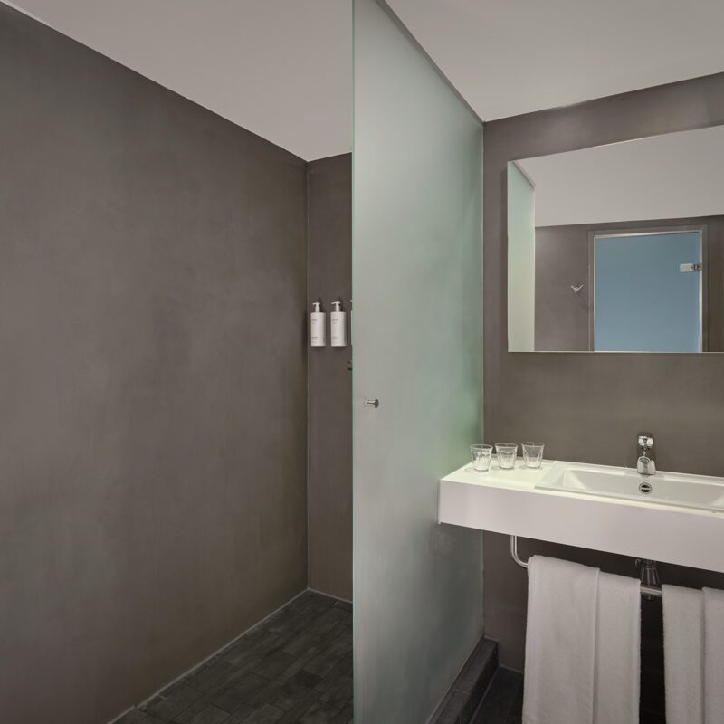 bathroom showing walk-in shower with ESPA amenities and sink with 3 glasses and towels