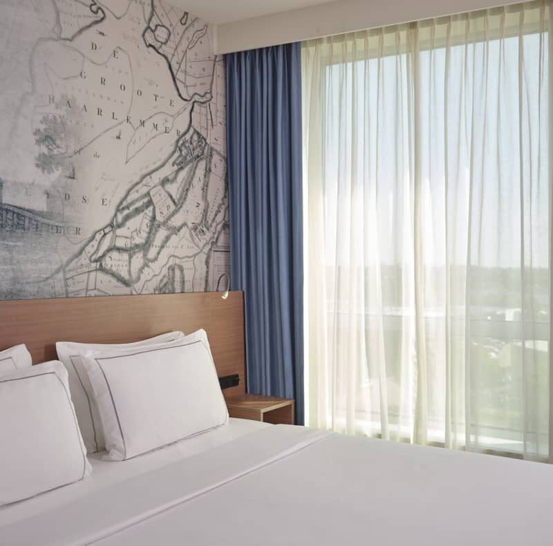 Closeup of double bed with curtains showing outside view