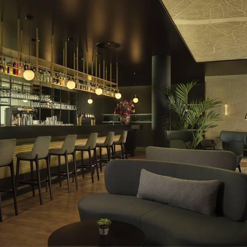 bar with 6 grey bar stores, bright blurb circular lights and rounded comfortable couches very sleek and sexy vibe