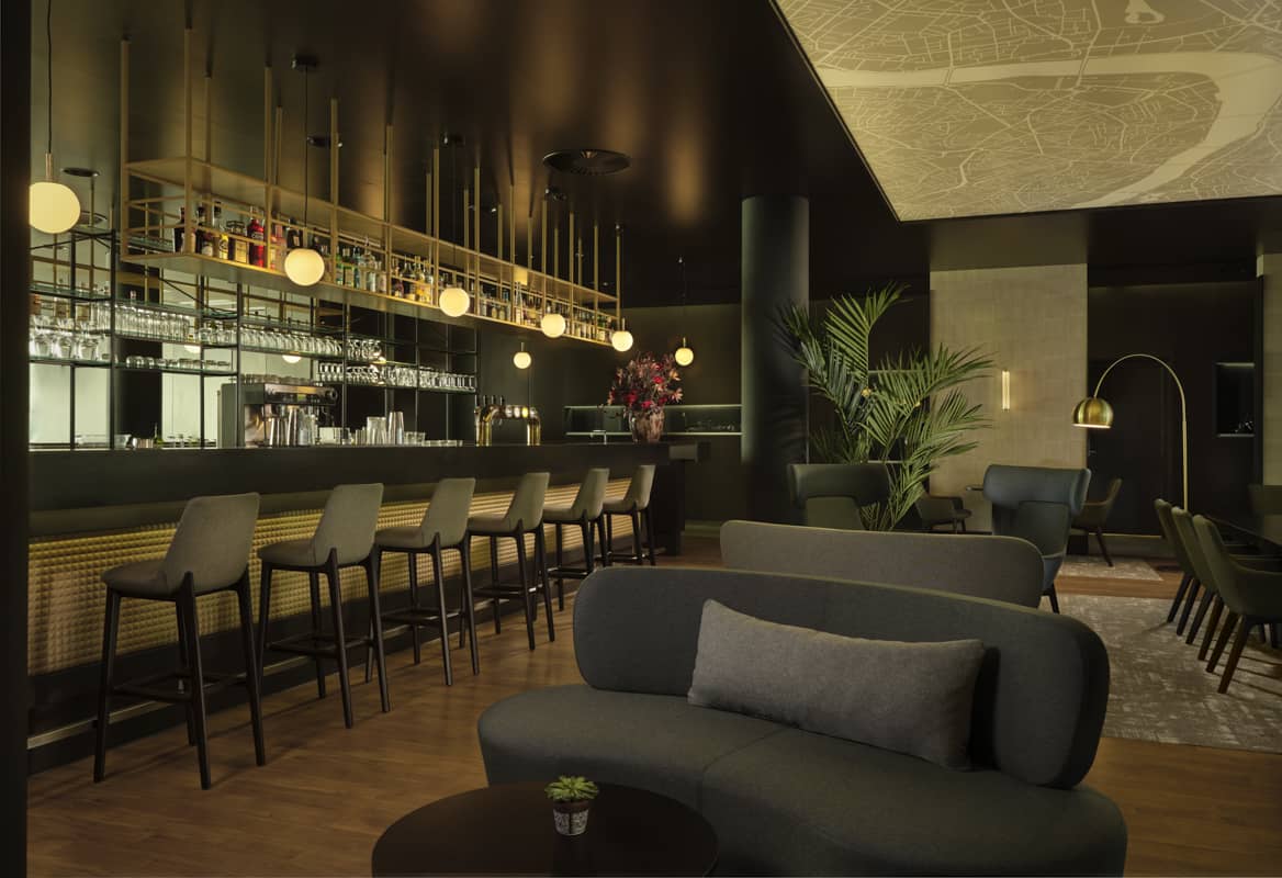 bar with 6 grey bar stools, bright blurb circular lights and rounded comfortable couches very sleek and sexy vibe